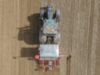 Top-down shot of a tractor tilling a barren field, cultivating soil for agriculture.