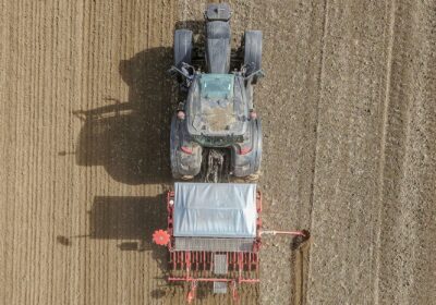 Top-down shot of a tractor tilling a barren field, cultivating soil for agriculture.